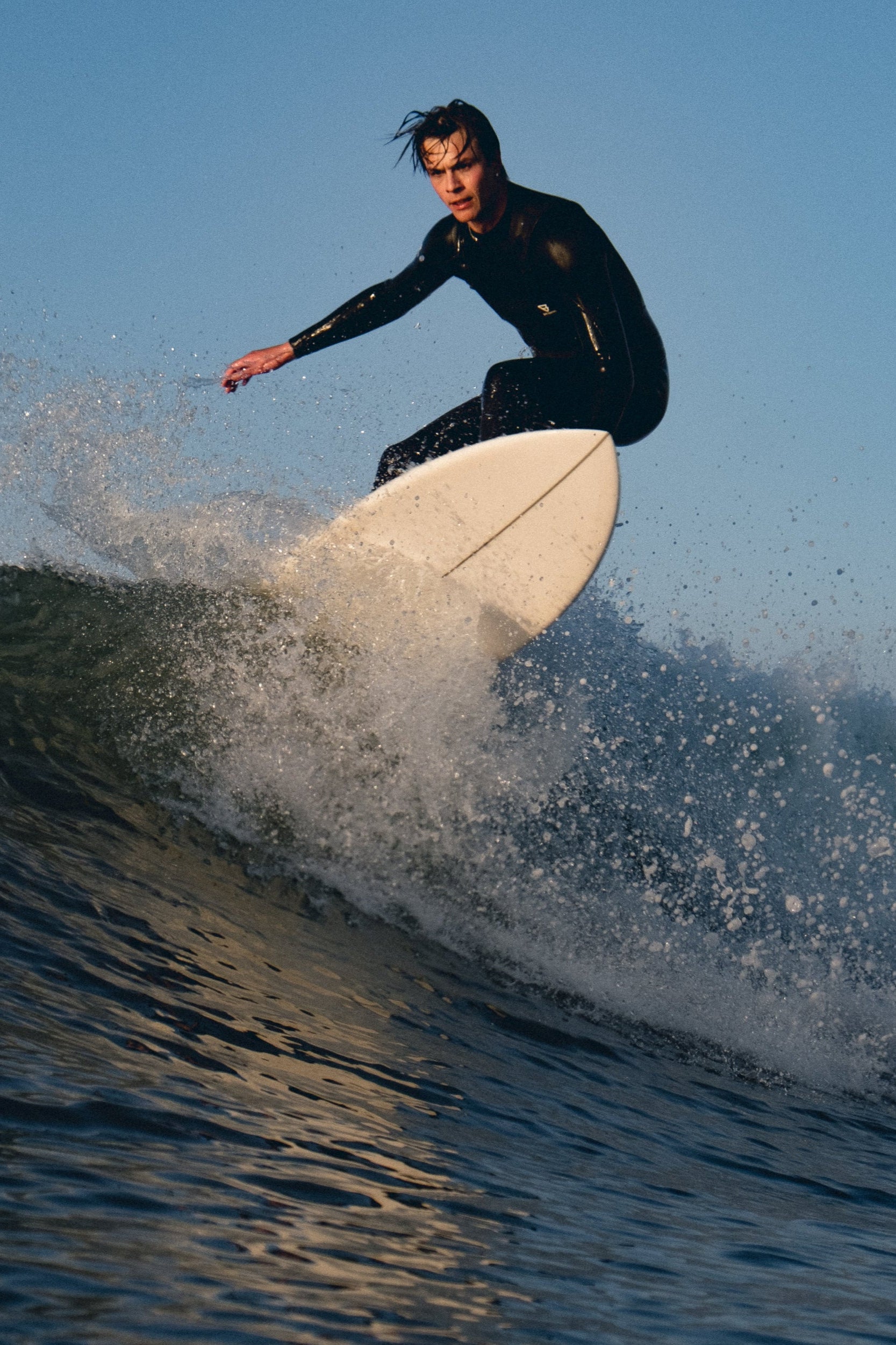Person surfing on a wave with a clear blue sky